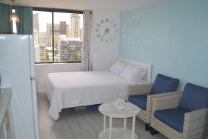 a small room with a bed and two chairs and a table at Hawaiian Monarch 1611 condo in Honolulu