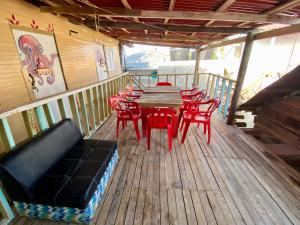 a wooden deck with a table and red chairs at Eco Hostal Estrella De Mar in Isla Mucura