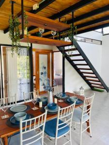 a dining room with a table with chairs and a staircase at Chega de Saudade in Puerto Quito