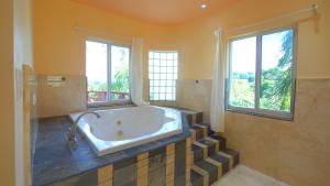 baño grande con bañera y 2 ventanas en Royal Palms Estate, en Christiansted