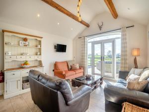 a living room with leather furniture and a large window at Bank House Barn in Audlem