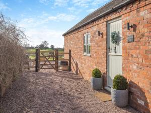 a brick building with a door and a fence at Bank House Barn in Audlem