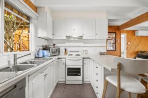 a white kitchen with white cabinets and a sink at Torquay Boulevard Beach House in Torquay +6 photos
