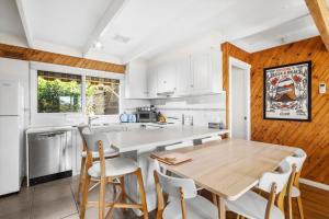 a kitchen with a wooden table and white cabinets at Torquay Boulevard Beach House in Torquay
