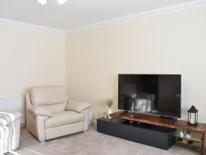 sala de estar con TV de pantalla plana y silla en Rycon en Turriff