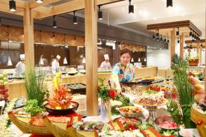 串本町にある大江戸温泉物語 南紀串本の食べ物の並ぶビュッフェの前に立つ女