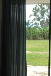 a window with a green curtain and a field of grass at The Woodlands Hideaway - A Brand New Family Friendly Guesthouse in Browns Plains
