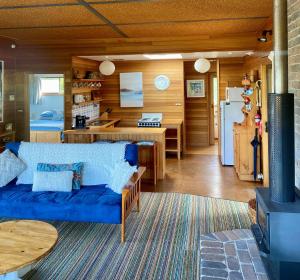 a living room with a blue couch and a kitchen at Spring Beach Retreat in Spring Beach