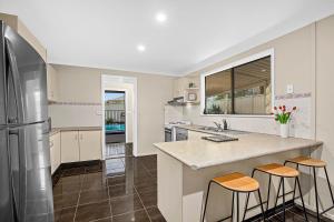 una cucina con frigorifero e 2 sgabelli da bar di Emerald Hub 1 and 2 a Emerald Beach