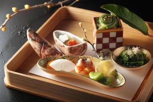 ein Tablett aus Holz mit Teller mit Lebensmitteln darauf in der Unterkunft Gora Kadan in Hakone