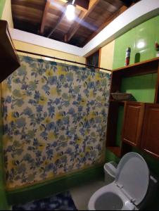 a bathroom with a shower curtain with a toilet at Casa Campestre in Bocas del Toro