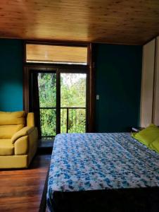a bedroom with a bed and a couch and a window at Casa Campestre in Bocas del Toro