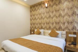 a bedroom with a large bed and a wall at OYO Flagship Hotel Shri Vilas in Bhopal