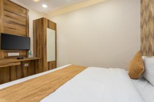 a bedroom with a large bed and a tv at OYO Flagship Hotel Shri Vilas in Bhopal