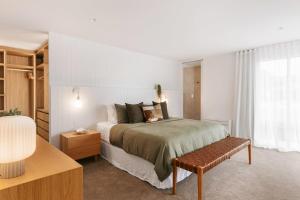 a bedroom with a bed and a bench in a room at 36 Marine - Unparalleled beachfront luxury in Mount Maunganui