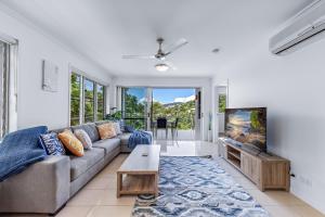 a living room with a couch and a tv at Airlie Summit Apartments in Airlie Beach