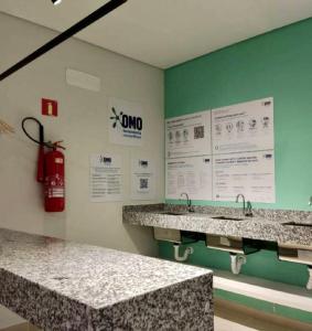 baño con 2 lavabos y extintor de incendios en la pared en Studio Green Brás, en São Paulo