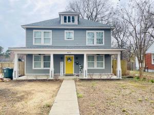 una casa gris con una puerta amarilla en un patio en Spacious home, 3 king beds, huge backyard near UM, en Memphis