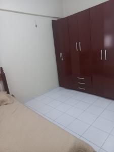 Pokój z brązowymi szafkami i białą podłogą wyłożoną kafelkami w obiekcie Apto Aconchegante em Fortaleza-CE w mieście Fortaleza