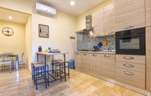 een keuken met houten kasten en een tafel met krukken bij 2 Bedroom Lovely Apartment In Catania in Catania