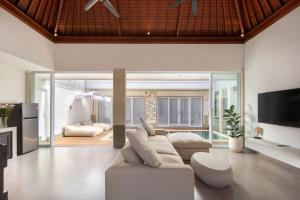 a living room with a white couch and a tv at Villa Bella Rose Canggu in Canggu