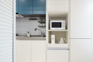 a kitchen with white cabinets and a microwave at Urbanstay Sokcho Beach AB in Sokcho