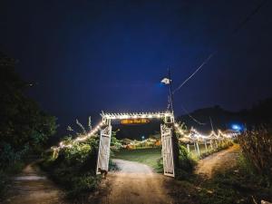a gate with lights on a dirt road at night at WIND HILL HOMESTAY HÀ GIANG in Làng Me