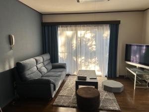 uma sala de estar com um sofá e uma televisão em Guest House Fuji no Yado Akebono Building A - Vacation STAY 74316v em Fujiyoshida