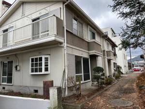 uma casa branca com uma rua em frente em Guest House Fuji no Yado Akebono Building A - Vacation STAY 74316v em Fujiyoshida