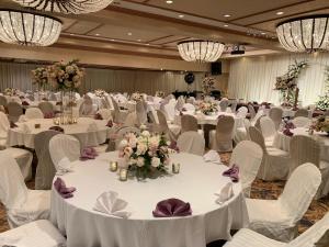 un salón de banquetes con mesas blancas, sillas y flores en Oxford Palace Hotel en Los Ángeles