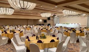 um salão de banquetes com mesas, cadeiras e lustres em Oxford Palace Hotel em Los Angeles