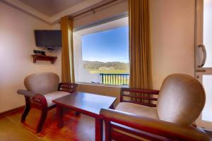 une chambre avec deux chaises, une table et une fenêtre dans l'établissement Eden Hill Hotel, à Nuwara Eliya