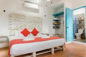 a bedroom with a large bed with red pillows at Casa Toloc Tulum in Tulum