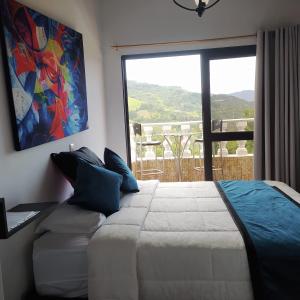 1 dormitorio con cama grande y ventana grande en Cozy 2-BR Apt with mountain view, en Medellín