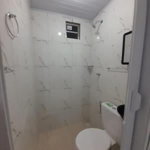 a bathroom with a toilet and a white tiled wall at Pousada Estelita in Itaparica Town