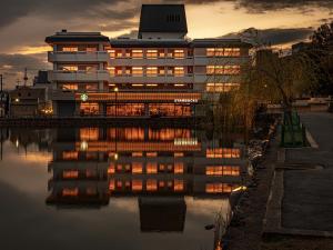 a building with its lights on reflecting in the water at Hotel Tenpyo Naramachi in Nara