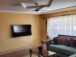 a living room with a couch and a flat screen tv at Casa Consuelo Guest House in Takoradi