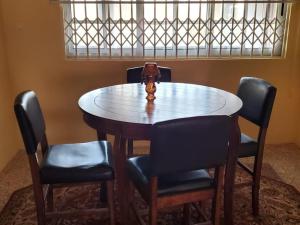 una mesa con sillas y un jarrón encima en Casa Consuelo Guest House, en Takoradi