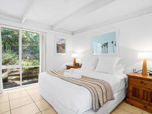 a white bedroom with a bed and a window at Quarterdeck in Portsea