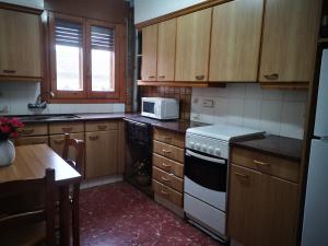 a kitchen with wooden cabinets and a white stove top oven at Ca la conxita in Tona