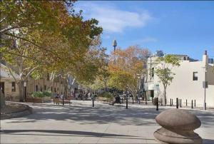 a city street with trees and people sitting on benches at Cosy Cottage Funky ICC Darling Harbour Sydney in Sydney
