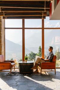 a man sitting in a chair in front of a large window at Shinta Mani Mustang - A Bensely Collection in Jomsom