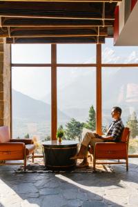 a man sitting in a chair in front of a large window at Shinta Mani Mustang in Jomsom