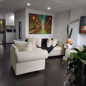 ein Wohnzimmer mit einem weißen Sofa und einem Gemälde in der Unterkunft Cozy 2-BR Apt with mountain view in Medellín
