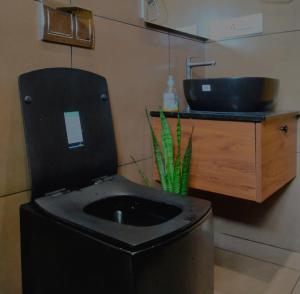 a bathroom with a black toilet with a sink at Mountain View Villa in Mukkam