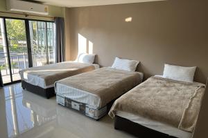 two beds in a room with a window at V Tharm Hotel in Udon Thani