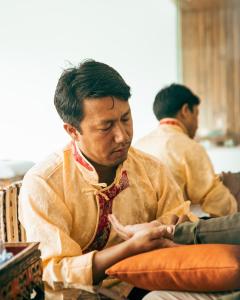 a man wearing a shirt and tie sitting on a pillow at Shinta Mani Mustang in Jomsom