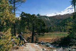 a man sitting on a hill next to a lake at Shinta Mani Mustang in Jomsom