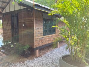 une cabane en bois avec un palmier en face de celle-ci dans l'établissement Up The Farm Udon Thani Farm Stay, 