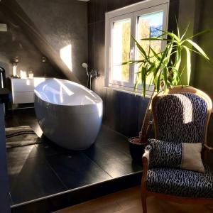 a bathroom with a large tub and a chair and a plant at Maison de 3 chambres avec piscine privee jacuzzi et wifi a Walbach in Walbach